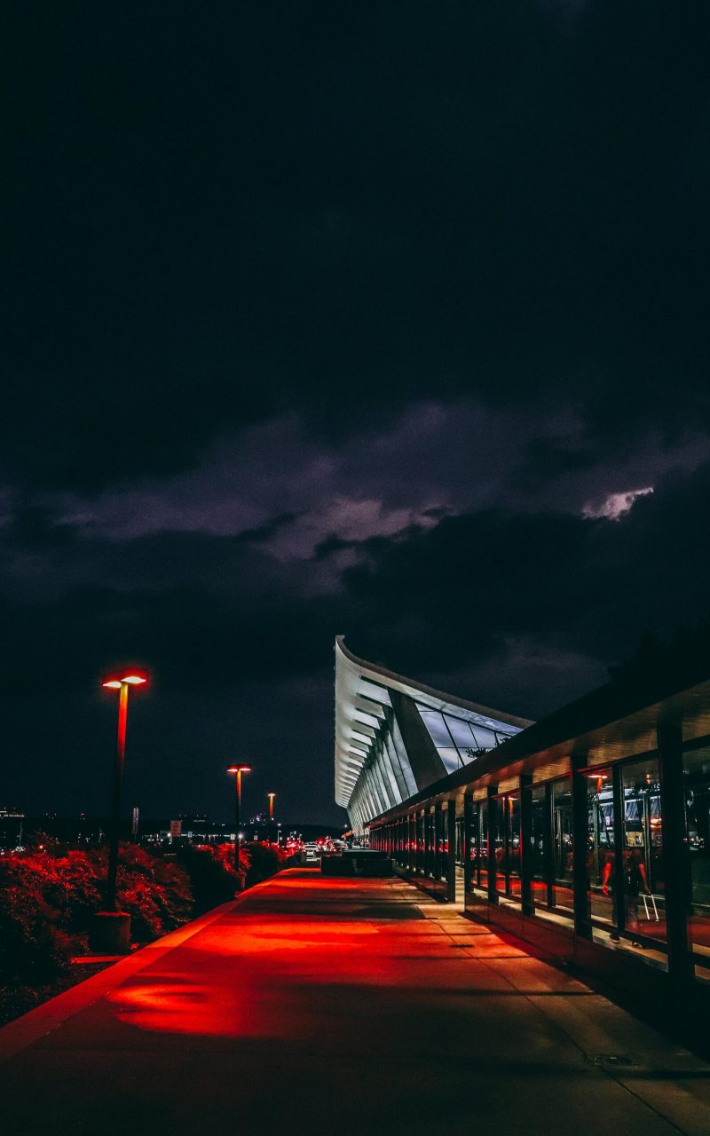 Stunning night scene capturing the illuminated architecture of Dulles Airport under a dramatic sky.